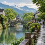 Umbrella-carrying visitors beside a lush southern Chinese canal after May rain