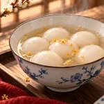 Round white tangyuan in a bowl of clear broth